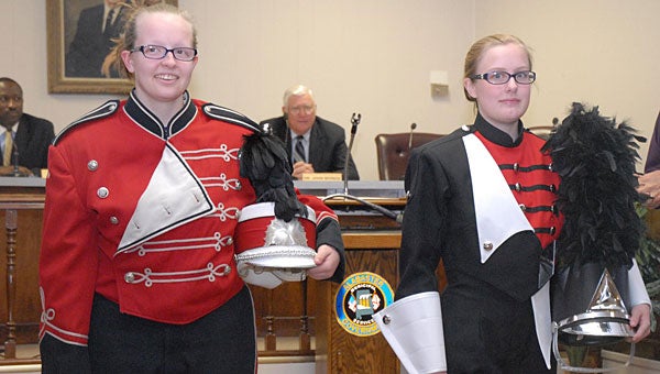 Thompson High School band members Suzanne Berry, left, and Mary Beth Moore, right, give the Alabaster School Board members a comparison of the band's old uniform, left, and the new uniform, right, during a recent meeting. A dunking booth at this weekend's CityFest will raise money to pay off the new uniforms. (File)