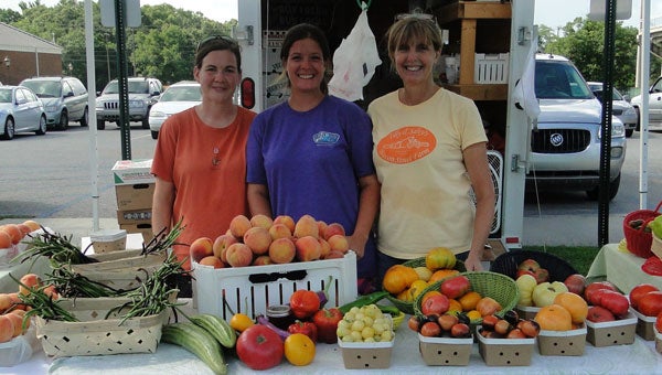 Boozer Farms owner Taylor Hatchett (middle), Rebecca Laatsch (left) and Hatchett’s mom Sonya Boozer sell fresh produce at Calera Farmers Market. (contributed)