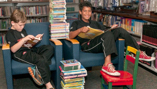 Caleb Bradley, left, and his brother Canaan, pictured with 105 books. Multiply by 7 to get a mental picture of the number of books Canaan read in the JHPL summer reading program. (contributed)