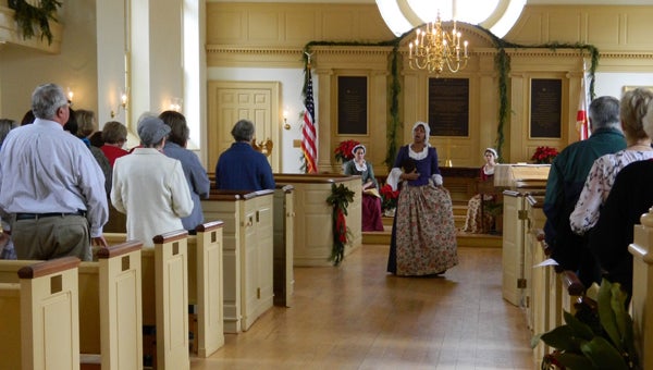 American Village visitors sing carols in the chapel as part of A Colonial Christmas at American Village last year. (Contributed)