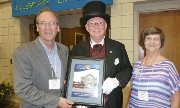 Alabama Historical Association President Lonnie, Burnett, Shelby County Historical Society President and Executive Director Shelby County Museum and Archives Bobby Joe Seales and wife Diane Seales at the AHA Fall Pilgrimage that coincided with the Columbiana Quilt Walk. Burnett on behalf of AHA gave Seales a framed copy of the Shelby County Museum with the Columbiana Trolley in front as a memento of the pilgrimage visit to Columbiana and Shelby County in October 2014. (Contributed)