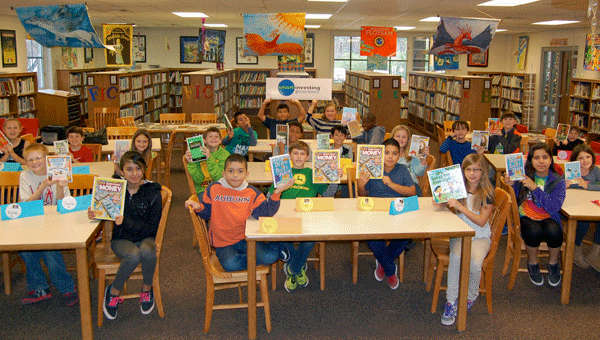 VIS students show off some of the books the Pelham Public Library donated to the school's library on Dec. 9. (Reporter Photo / Molly Davidson)