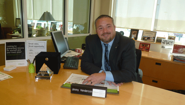 Jimmy Henderson, branch manager of the Columbiana Regions Bank, sits at his desk with the diamond-shaped Regions Bank Better Life Award that he recently won for his outstanding professional work at Regions and in the community fostering children. 