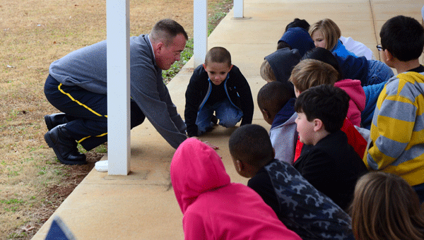 Fire Department Lt. Chip Brantley, left, shows local second-graders how to "Get low and go" during a visit to Meadow View Elementary on Nov. 25. (Reporter Photo/Neal Wagner)