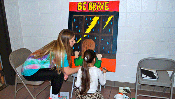 OMHS junior Sarah Kathryn Hicks helps an OMES student paint on Jan. 8. (Reporter Photo / Molly Davidson)
