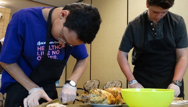 Matthew Leon and Isaac McCannan carve roasted chicken during Thyme to Cook for Teens Cooking Academy on July 7. (Contributed)