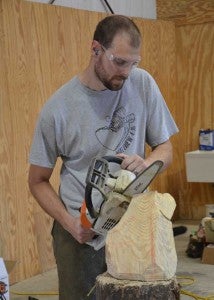 Justin uses a chainsaw to create a sculpture. 