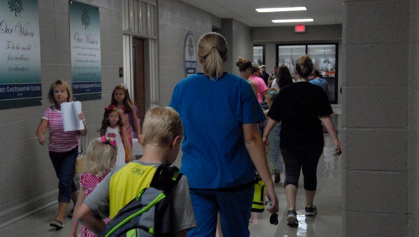Parents walk their children into Forest Oaks Elementary School on Aug. 12, the first day of the 2015-2016 school year for Shelby County Schools.