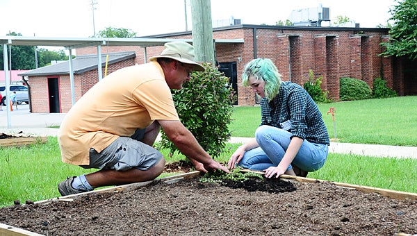 Girl Scout Sarah Messer and Myers Plants and Pottery owner Stewart Myers work on a flowerbed for special-needs students at Thompson Intermediate School on Aug. 19. (Reporter Photo/Neal Wagner)