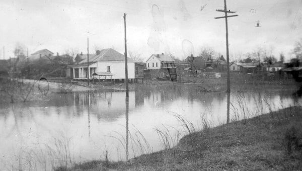 Buck Creek Flood. This 1930s photo shows water backed up by Buck Creek covering First Avenue at Branch Alley. The second story of the Masonic Lodge, now the Helena Museum, can be seen on the far left. This and many other photographs were shared with the City of Helena Museum by Carol Nunnally Black. (Contributed/City of Helena Museum)