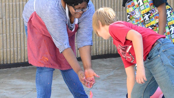 A volunteer from Calera High School helps a student pop a paint filled balloon at the Linda Nolen Center’s Art from the Heart Festival Oct. 13. Reporter photo / Jessa Pease  