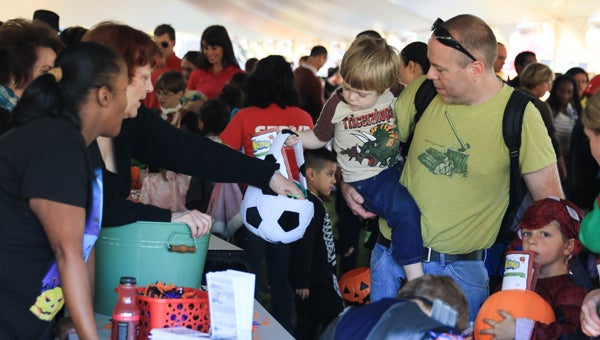 A family trick-or-treats from local Hoover businesses during the Oct. 29 Hoover Hayride and Family Night at Veterans Park. (For the Reporter / Dawn Harrison)