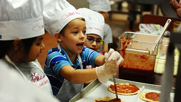 Creek View Elementary School first-grader Jackson Brashier, center, prepares a pizza at the school on Oct. 8 while his classmates Jocelyn Robes-Brito, left, and Audrey Nickell, right, look on. (Reporter Photo/Neal Wagner)
