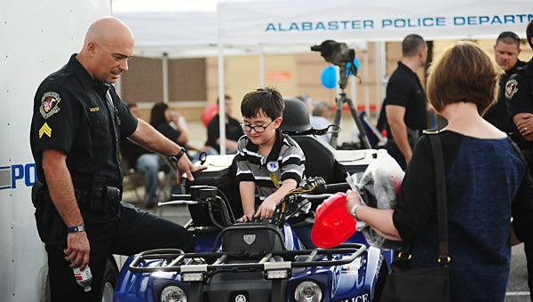 Alabaster police officer Chad Wooten, left, shows Caleb King the controls on the department's four-wheeler during National Night Out on Crime at the Alabaster Target on Oct. 6. (Reporter Photo/Neal Wagner)