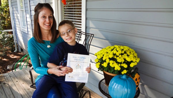 Amy Roux and her 7-year-old son, Austin, display a teal pumpkin and sign at the Chelsea Public Library advertising the Teal Pumpkin Project, a campaign aimed at raising awareness of food allergies. (Reporter Photo/Emily Sparacino)