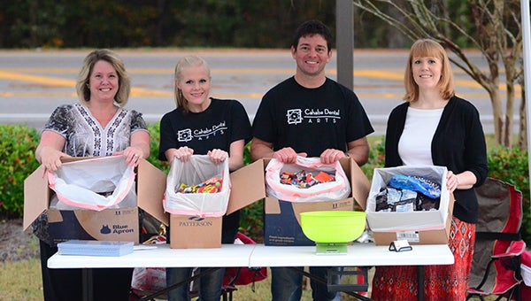 Members of local Helena businesses show off the candy collected from the Halloween buy back program. (Reporter Photo/Graham Brooks)
