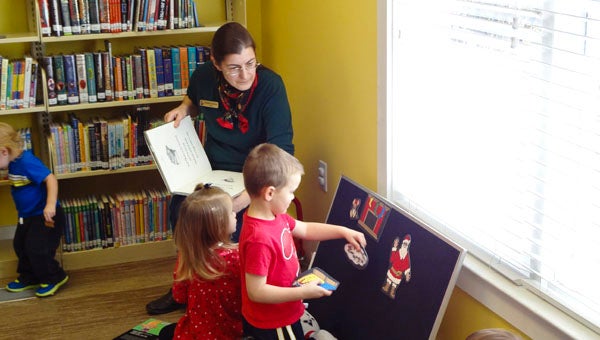 Children place felt pieces on a flannel board as Chelsea Public Library employee Elisabeth Graham reads "The Night Before Christmas" during Tot Spot on Dec. 16. (Reporter Photo/Emily Sparacino) 