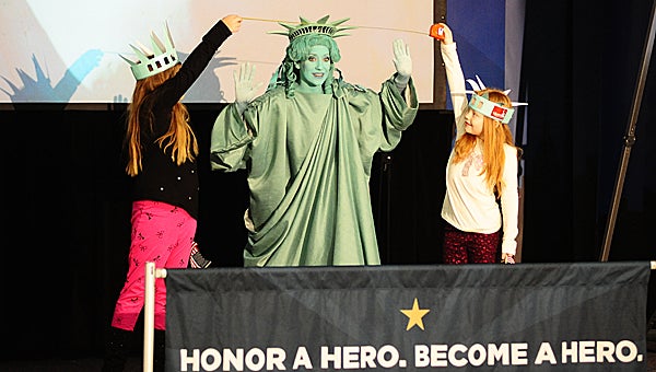 Meadow View Elementary School second-graders Kortney Carter and Kaelyn Smith help Libby Liberty demonstrate the length of the Statue of Liberty’s mouth during a Jan. 8 assembly at the school. (Reporter Photo/Neal Wagner)