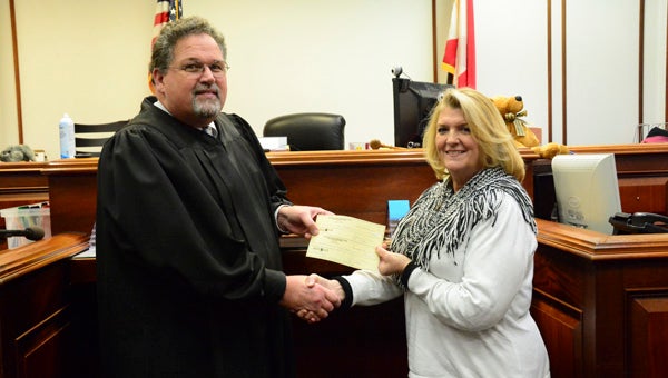 Shelby County District Court Judge Jim Kramer presents two checks, each for $2,500, to Shelby County Schools Jobs Coach Cindy Vinson on Feb. 5 for the HOPE (Herbs Offering Personal Enrichment) program. (Reporter Photo/Emily Sparacino)