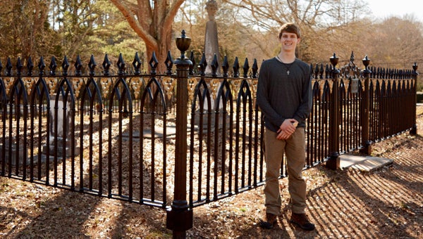 Ryan Harmon stands next to the Horace Ware Fence at the Columbiana City Cemetery.  Harmon recently renovated the fence, which was originally built in 1864, as his Eagle Scout project. (Contributed)