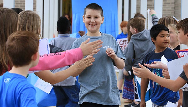 An HIS Special Olympics participant is greeted with high fives and applause from classmates as nine HIS students received a special send-off before competing in the Special Olympics games on March 23. (For the Reporter/Dawn Harrison)