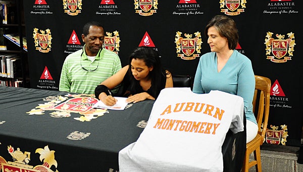 Thompson High School soccer player Allison Singleterry, center, signs a scholarship with Auburn University – Montgomery on March 18 while surrounded by her father, Dennis, and mother, Tammy. (Reporter Photo/Neal Wagner)