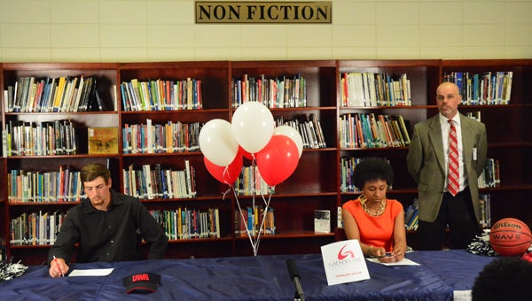 Zach Gaines, left, and Tyesha Haynes, right, listen to words from Calera principal Joel Dixon during a ceremony on April 19 where both athletes committed to furthering their athletic careers at the collegiate level. (Reporter Photo / Baker Ellis)