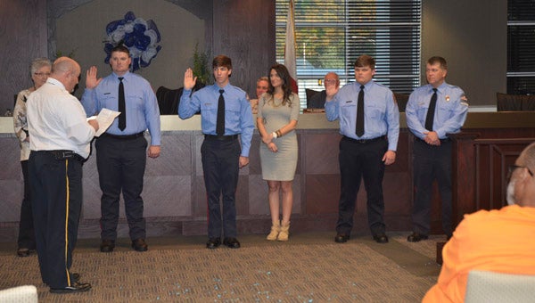 Chelsea Fire and Rescue's newest firefighters, from left, Andrew White, Andrew Shears and Zack Lee, raise their right hands as Fire Chief Wayne Shirley, far left, reads the Firefighter Code of Conduct at a Chelsea City Council meeting April 5. (Reporter Photo/Emily Sparacino)