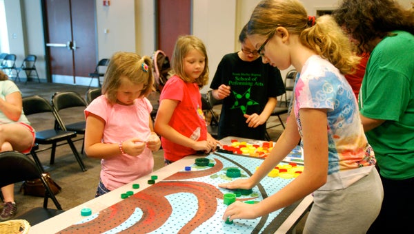 Children work on a bottle cap mural during an Art in Action program at the North Shelby Library. (Reporter Photo/Molly Davidson)