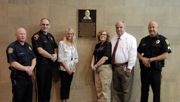 Pelham Police Officers and employees stand with a bronze plaque depicting Officer Philip Davis mounted on the wall of the police department. (File) 