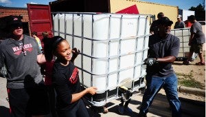 Students and teachers work to load large water containers onto an 18-wheeler to ship to Honduras. (Reporter Photo/Neal Wagner)