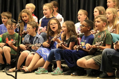 Third graders sing as they strum their ukuleles in a performance at Art in the Park. (For the Reporter/Dawn Harrison)