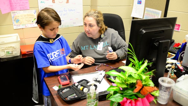 Mt Laurel Elementary School second grader John Henry Kirkpatrick, left, receives glucose tablets from school nurse Treasa Daly during one of his blood sugar checks May 25. Kirkpatrick, who has Type 1 diabetes, was honored with a Super Hero Day. (Reporter Photo/Emily Sparacino)