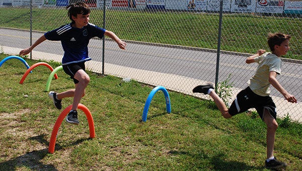 : Two campers compete at the hurdles station during a track and field youth summer camp at Helena High School on Thursday, June 23. (Reporter Photo/Graham Brooks)