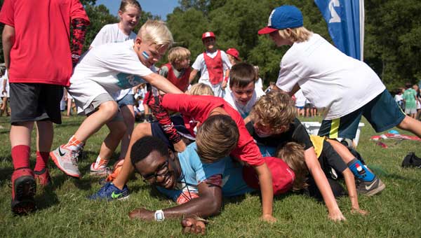 Campers celebrate by piling on their group leader after their group won a game July 21 at WinShape summer camp hosted by Double Oak Community Church.
